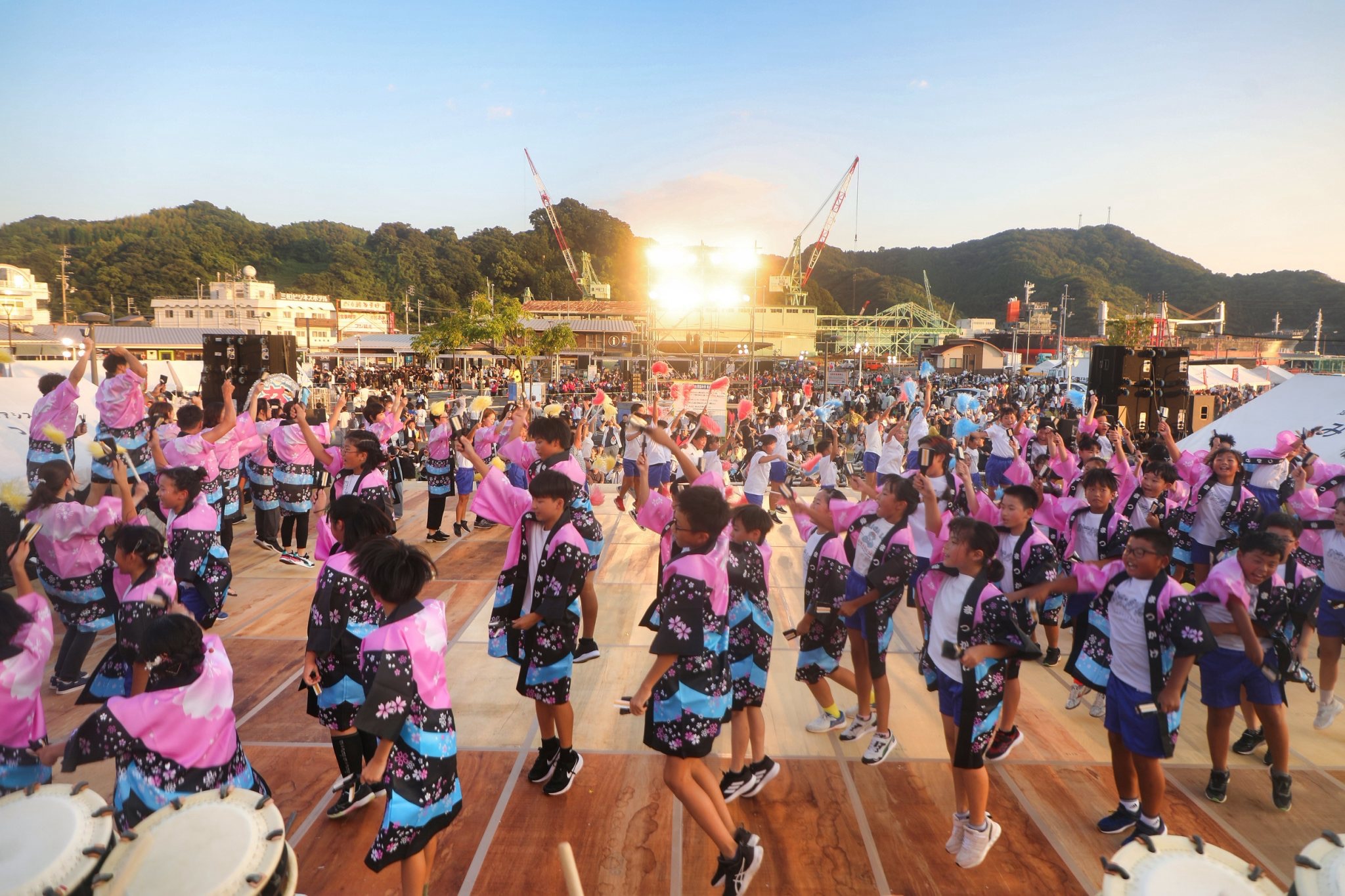 夕暮れの会場で、太鼓と踊りを披露する子どもたち